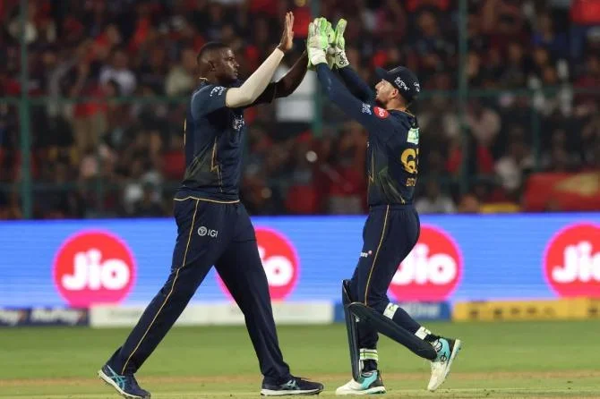 Gujarat Titans' Jason Holder and Jos Buttler celebrate the wicket of Royal Challengers Bengaluru's Virat Kohli